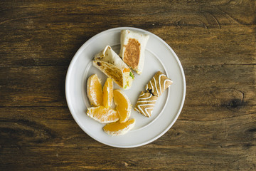 plate of healthy food consisting of breakfast burrito, oranges, and nutrition bar