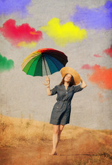 Young brunet girl with colorful umbrella and clouds