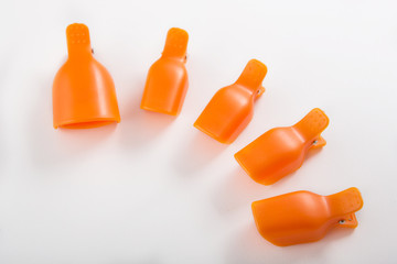 orange clothespins for removing nail polish on a white background