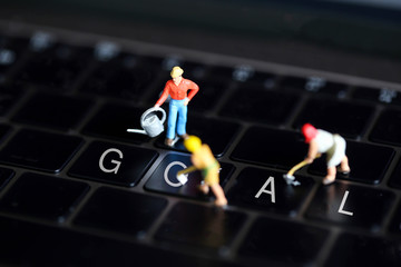 Miniature people : worker team with  button on a computer keyboard of GOAL.