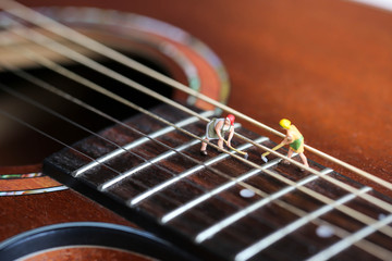 Fototapeta premium Miniature people : worker team with acoustic guitar,time of relax or music relax,stationary,education concept.