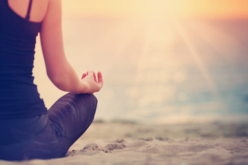 Fototapeta na wymiar young woman sitting on the beach and practicing yoga