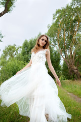 Obraz na płótnie Canvas young pretty bride in white wedding dress spin around