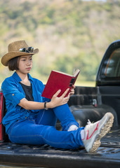 Woman wear hat and reading the book on pickup truck