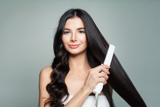 Attractive Woman With Curly Hair And Long Straight Hair Using Hair Straightener. Hair Problem And Haircare Concept