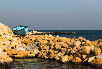 An old boat on the stones by the sea.