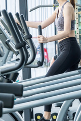 Asian sport woman doing some exercises with gym equipment in fitness club.