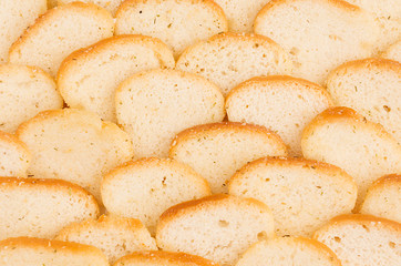White small croutons of ruddy loaf with spices closeup, pattern, top view. Fast food background.