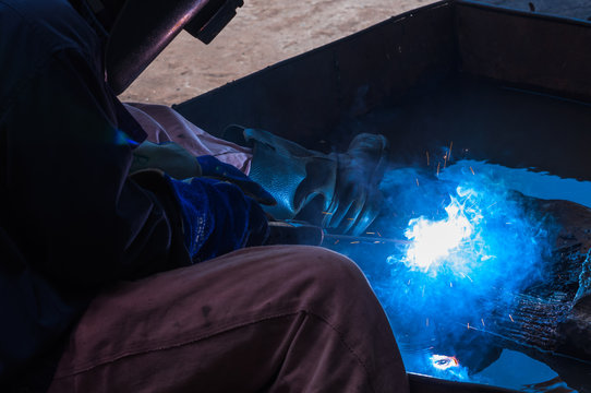 Industrial Worker labourer or welder at the Manufacturing factory welding metal or steel structure. Hot Work safety or Welding safety with masks and gloves to protect lights and sparks