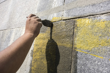 Man's hand is brushing along the wall. Rough wall finishing.