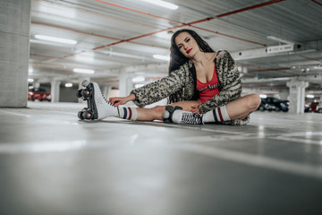 Fototapeta na wymiar young sexy woman rollerskating in an urban looking garage and posing in a hipster like matter