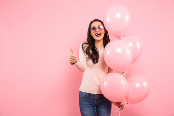 Portrait of cheerful woman with long dark hair wearing fancy glasses holding bunch of air balloons...