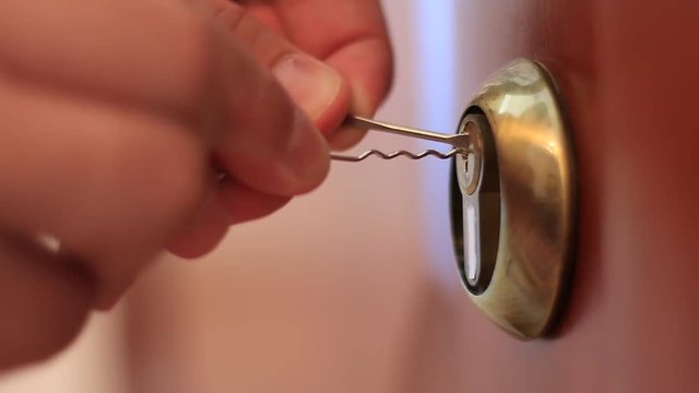 Hands opening the lock with picklocks