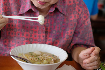 woman eating egg noodle soup with fish ball. Thai local food.
