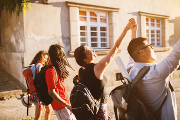 Four great friends holding hands in the air celebrating a fun time of a vacation in a city.