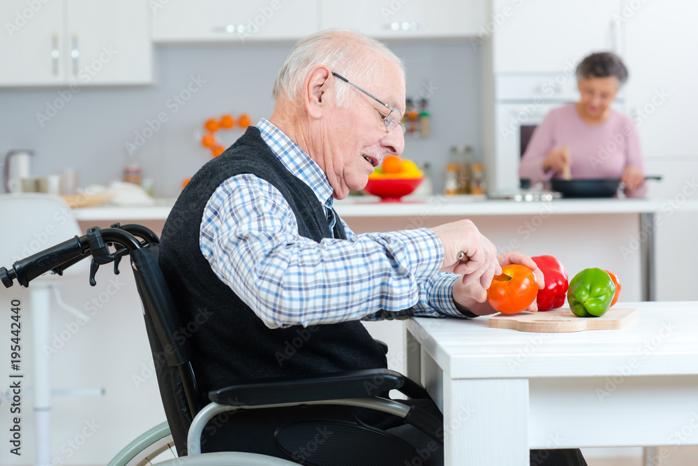 Wall mural senior couple cooking together - man disabled on wheelchair