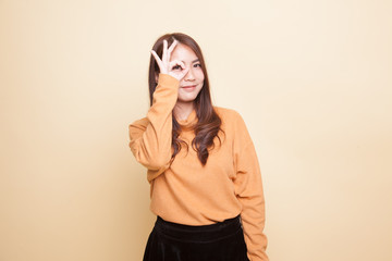 Beautiful young Asian woman show OK sign over her eye.