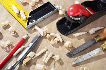 old  carpenter plane tools and wood shavings on wooden background.