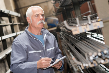 senior worker counting metal bars in warehouse