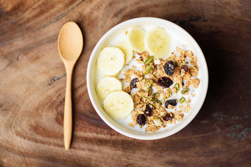 Healthy breakfast, muesli with cereal, slice banana and milk in a bowl, top view