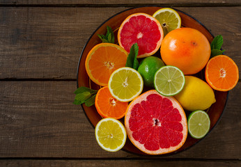 mixed citrus fruits on dark wooden background