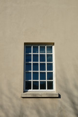 Big square window with small glazing pattern made of many mullions in a plastered building facade