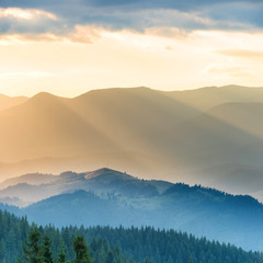 Beautiful sunset in the mountains. Landscape with sun shining through orange clouds