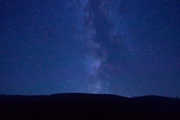 Fototapeta na wymiar Night dark blue sky with many stars and milky way galaxy above a mountain