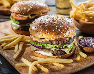 Hamburgers and French fries on the wooden tray.
