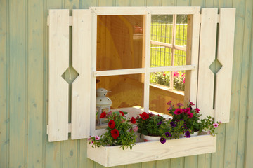 White wooden window with shutters and flowers on the windowsill