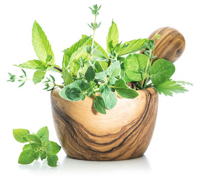 Different fresh green herbs in the wooden mortar.
