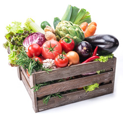 Fresh multi-colored vegetables in wooden crate.