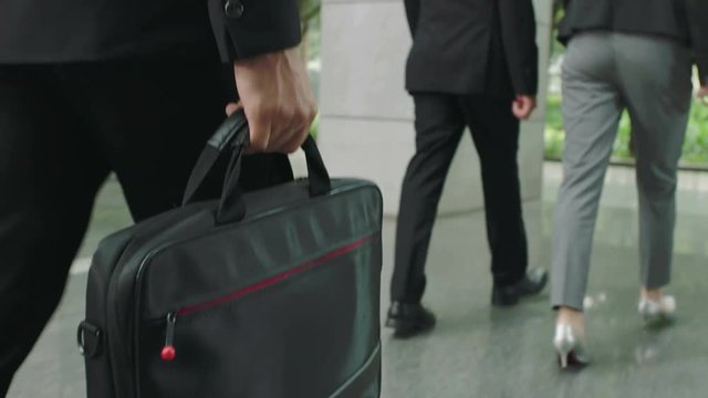 corporate people carrying computer bag walking out of modern building.