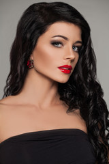 Perfect Brunette Model Face. Young Woman with Red Lips Makeup,  Long Curly Hair and Ruby Earrings