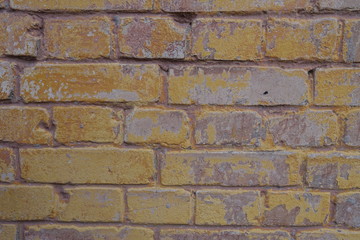 Fototapeta premium Remains of old yellow paint on brick wall