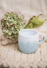 Earthenware crockery. White cup with blue sea and green hydrangea in it