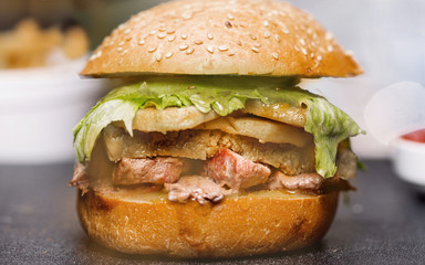 Delicious fried prawn and beef hamburger with salad and mayonnaise are served on a wooden wooden table. Side view. Close-up.