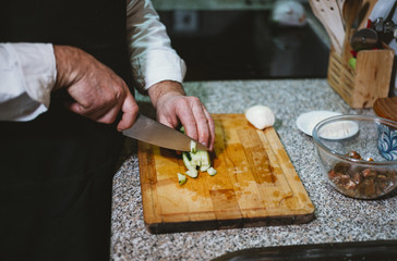 Man of 59 year old cutting vegetables in the kitchen of his house.