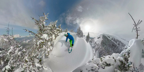 Freeride snowboarder riding fresh powder snow in snowy backcountry wilderness