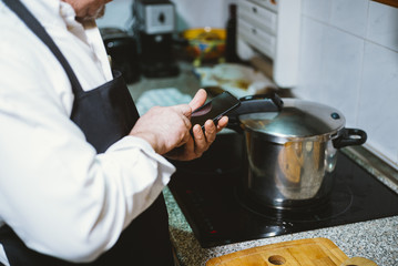 Man of 59 year old with smartphone in the kitchen of his house.
