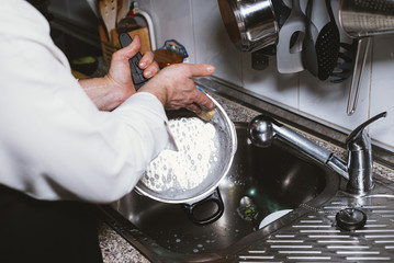 Man of 59 year old eat banana in the kitchen of his house.