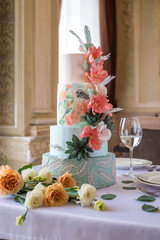 Home wedding for-tiered cake on the table in the restaurant decorated with pink roses and green leaves in a rustic style