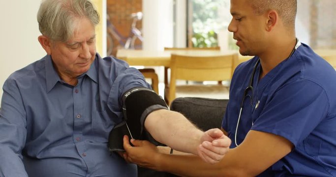 4K Doctor on a home care visit checking the blood pressure of elderly man. Slow motion