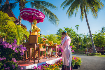 A woman this wearing traditional Thai dresses to pay respect to the Buddha statue on the occasion...