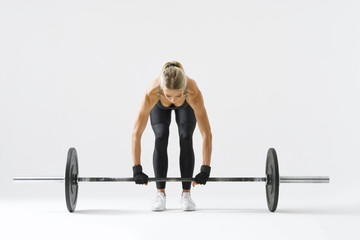 Fototapeta na wymiar Fitness attractive woman preparing to practice deadlift with heavy weights Female bodybuilder doing heavy weight lifting work out on white background Horizontal picture