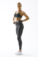 Full length portrait of fitness woman standing with her arms on hips Female model in sportswear over white background Mockup