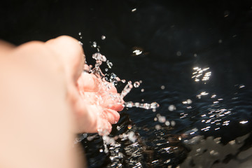 Hand fängt Wasser aus einem Fluss auf, Erfrischung und Trinken
