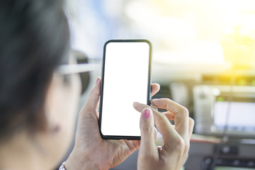 The middle-aged woman who wear sunglasses is holding mobile phone by hand while sitting on front seat in car