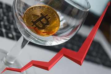 golden bitcoin on laptop background, red arrow is reflected in the glass