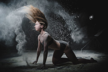 Fototapeta na wymiar Girl dansing with flour on black background